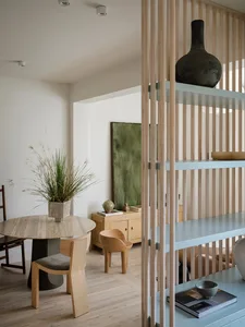 A modern minimalist living room with concrete floor, wooden furniture, and metal elements.