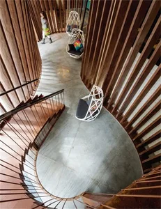 A modern lounge area with wooden floors, spiral stairs, and hanging rattan chairs.