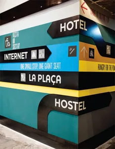 Multi-colored directional signage with text and icons indicating hotel, internet, la plaza, and hostel locations within an in