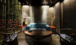 A modern living room with a metallic accent wall, blue sofa, and round wooden coffee table.