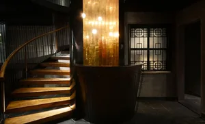 Modern interior design featuring a lit wooden staircase next to a circular bar.