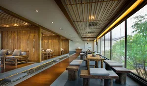 Bamboo restaurant interior with wooden flooring and seating, stone pathway, and large windows.