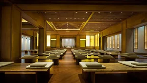 Large, wooden meditation room with multiple benches and cushions.