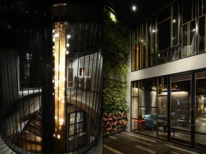 An interior residential lounge featuring metal and glass elements with green plants.