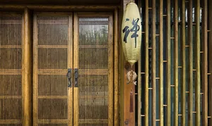 A minimalist wooden door with a traditional Japanese lantern hanging on the side, featuring Chinese characters for 'zen' and 