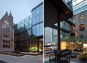 Modern hotel lounge with glass exterior and brick courtyard, featuring contemporary design elements and natural light.