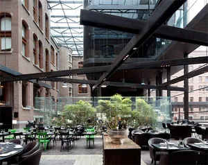 Restaurant interior featuring a modern industrial design with glass, concrete, and steel elements.