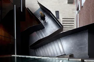 A modern, metal interior with a spiral staircase and a woman walking down the stairs.