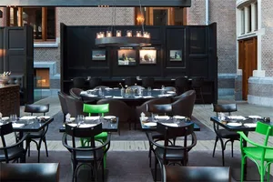 A modern restaurant interior featuring black metallic furniture adorned with green accents, including green chairs and green 