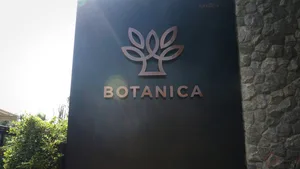 A black outdoor sign with a metallic leaf motif displaying 'BOTANICA'.