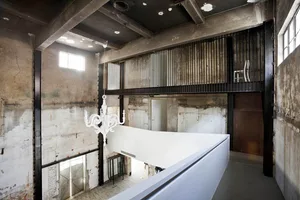 An industrial commercial space renovation featuring a concrete wall and balcony.