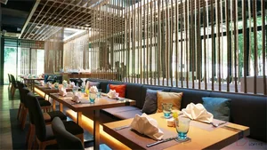 Modern minimalist restaurant interior with wooden benches, fabric cushions, and glass dividers.