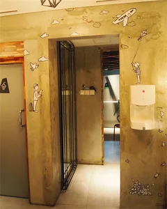 An image of a modern corridor decorated with painted concrete walls featuring clouds and birds, with a hand dryer on the righ