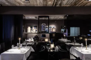 A modern dining room with wooden walls, glass elements, and fabric seating.