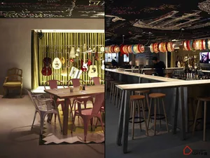A modern industrial restaurant interior featuring metal and wooden furniture, a chalkboard with graffiti, and colorful lanter