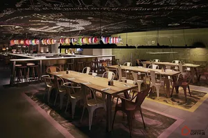 Modern industrial restaurant interior with wooden furniture, chalkboard ceiling, and colorful lanterns.