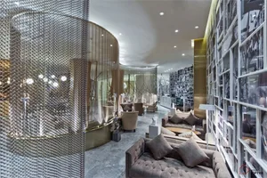 Modern hotel lounge with metal chain curtains, glass tables, and plush seating.