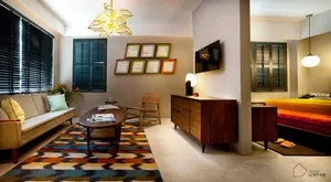 A modern living room with a colorful patterned rug, mid-century modern furniture, and a geometric chandelier.