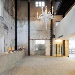 Industrial-style lobby featuring exposed concrete walls and a white chandelier.