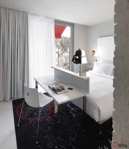 A modern minimalist bedroom with a white color palette, featuring a white bed, a white chair, and a white desk with a black r