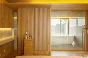 A modern minimalist bedroom with wooden walls and a glass door leading to a bathroom.