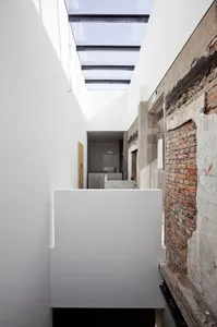 A minimalist interior with a modern, concrete wall and a skylight