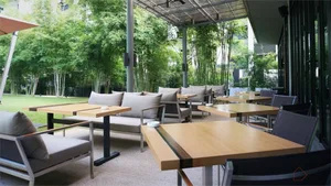 現代戶外餐廳露台，木質餐桌搭配金屬椅，四周環繞綠意與竹子