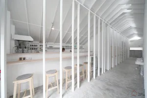 A minimalist cafe bar interior with concrete floors and white walls.