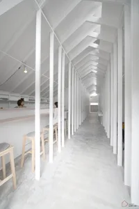 Exterior view of a minimalist cafe with concrete walls and wooden accents.