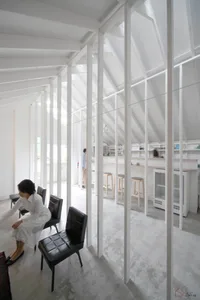 Interiors of a minimalist white space featuring concrete flooring and furniture.