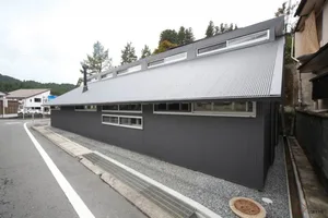 Modern residential building with metal walls and a large overhanging roof.
