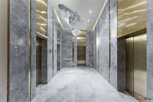 A modern office corridor with marble walls and floors and hanging art installations.