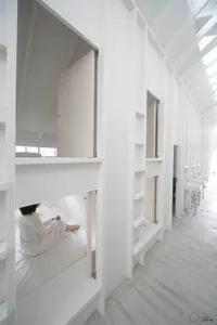 A minimalist bedroom with white walls and wooden furniture.