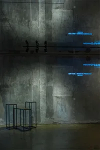 A minimalist industrial installation with concrete walls and an abstract metal structure.