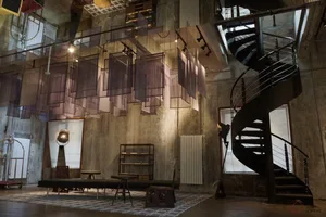 An industrial-style interior with concrete walls, fabric installations, and a spiral staircase.