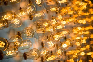 Multiple clear glass light bulbs with an industrial spiral filament hanging on a wall.