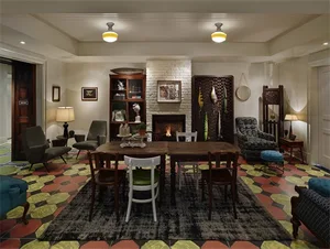 A cozy, industrial-style living room with a fireplace, wooden table, chairs, and a patterned rug.