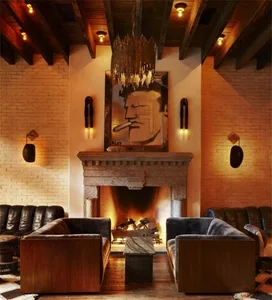A cozy industrial-style living room with brick walls, wooden beams, and a stone fireplace.