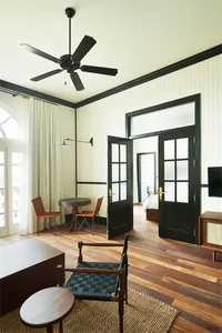 A stylish, industrial-themed living room with wooden flooring, black-framed windows, and a minimalistic design.