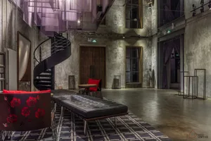 Industrial-style loft space featuring concrete walls, a spiral staircase, and minimalist furniture.