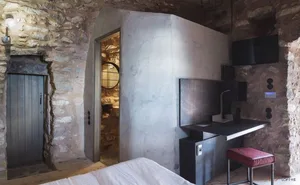 A minimalist bathroom with concrete walls and a white bed.