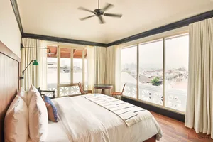 A modern, minimalist bedroom featuring a large window overlooking a cityscape.