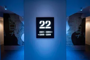 Metallic door numbers on a blue background in a minimalist interior design setting.