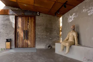 A minimalist interior design featuring concrete walls and a plaster column with a wooden sculpture and floor plan.