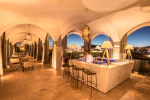 Modern bar interior with marble furniture and seating, overlooking a cityscape.
