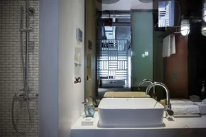 Modern bathroom with a concrete sink, white counter, tiled shower, and industrial lighting.