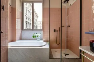 A modern bathroom featuring marble, pink tiles, and a view of the city.