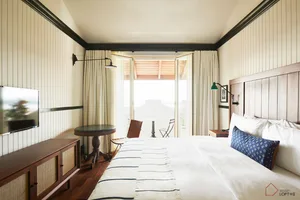 Modern bedroom featuring a white bed with wood details and a striped blanket.