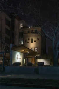 Modern building with brick exterior at night, illuminated by warm lights.