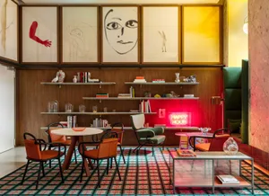 A modern cafe bar interior with a mix of materials and colorful elements, featuring a round table, chairs, shelves, and a neo
